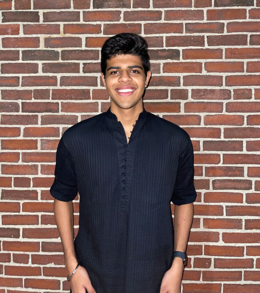 Aryan standing against the backdrop of a brick wall